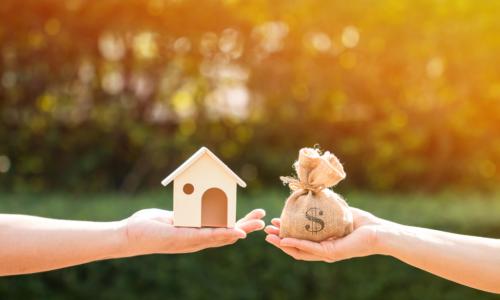 a man and a women hand holding a money bag and a toy-sized model home