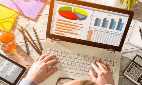 business owner working with accounting software on his laptop, unused calculator and notebook off to the side