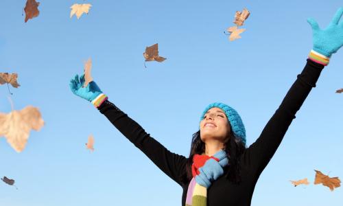 woman throwing fall leaves in the air