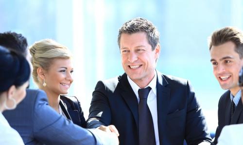 executives around table with two of them shaking hands