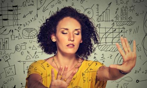 woman in a yellow blouse with eyes closed putting hands out in front onto charts and graphs