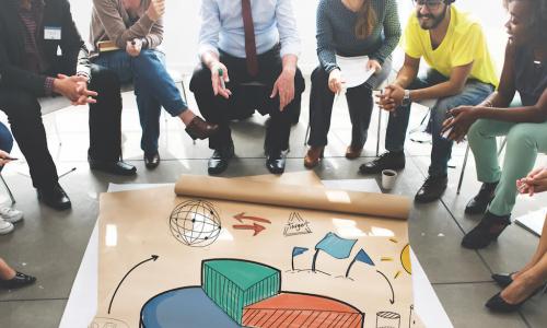 group of professional workers sitting in a circle looking at a colorful graph on the floor