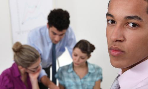 African American business man looking worried with colleagues blurred in the background