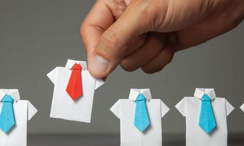 hand picking a paper dress shirt with red tie out of a row of paper shirts with blue ties