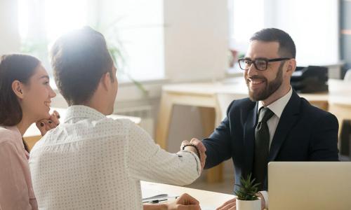 smiling customer service representative shaking hands and greeting a couple