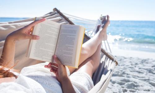 woman reading on the beach in a hammock