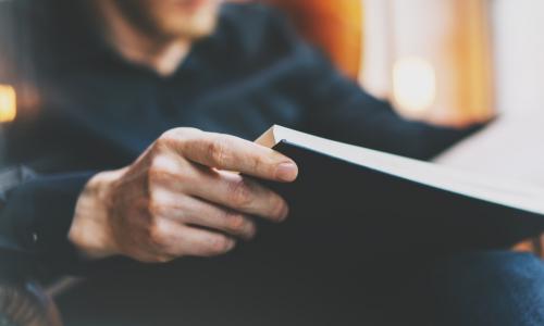 man reading book in leather arm chair