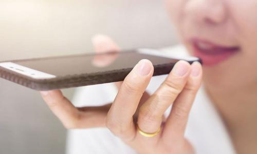 woman speaking into a smartphone to use voice search