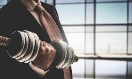 executive in a business suit lifting dumbell