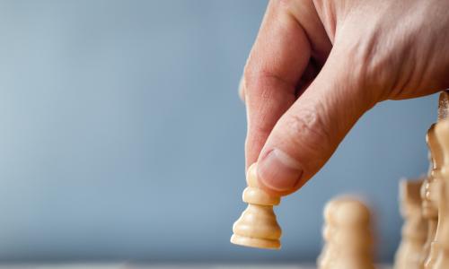 hand moving chess pawn on blue background