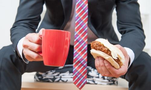 executive eating sloppy joe and drinking coffee