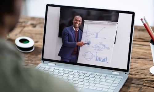 man watches executive present on laptop screen