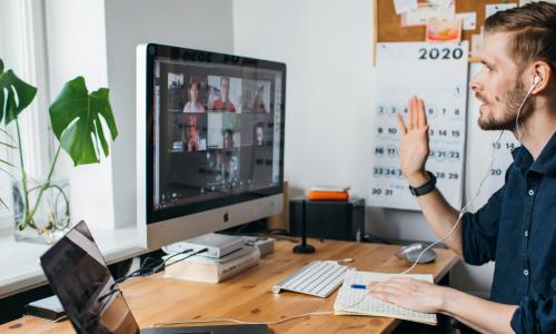 young male employee video conferencing with coworkers