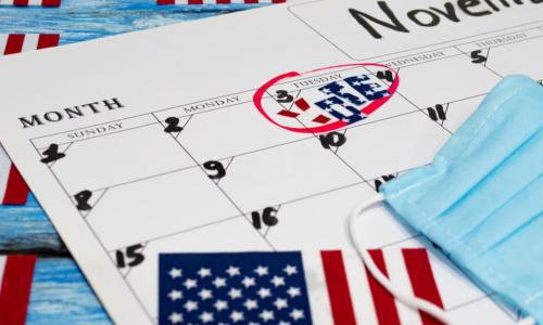 calendar with election day marked surrounded by U.S. flag and surgical mask