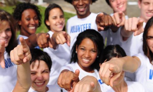 diverse volunteers in white volunteer shirts pointing