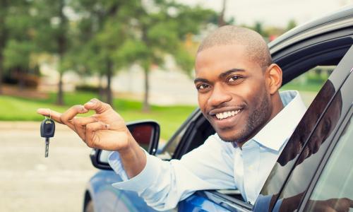 man in blue car leaning out window with key