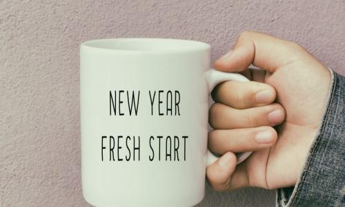 person in jean jacket holding mug with words new year fresh start written on it