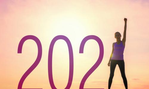 woman with arm up and fist next to a 2021 sign in the sun