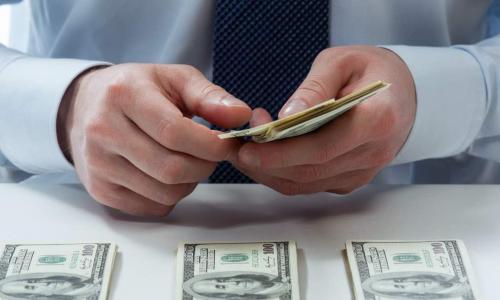 man's hands counting dollar banknotes on the table