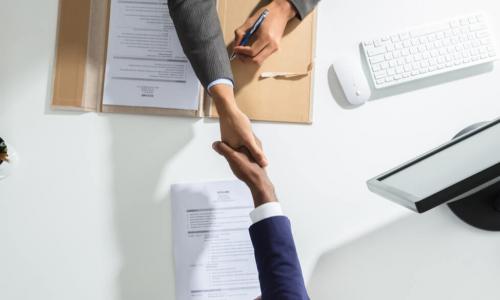 high-angle shot of two businesspeople shaking hands across a table