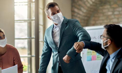 description businessmen do an elbow bump in masks at meeting with another businesswoman