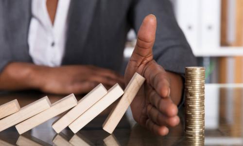 female executive using hand to stop domino-shaped blocks from falling in sequence