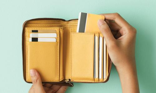 hand pulls payment card out of tan and yellow leather wallet