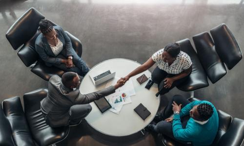 committee of black people having a handshake over a table