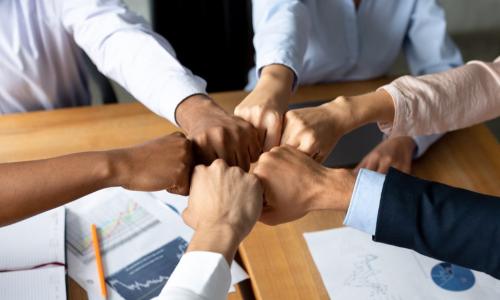 diverse fists together over a table with papers about finances