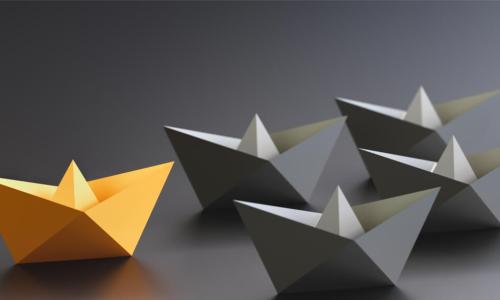 yellow paper boat leading black paper boats