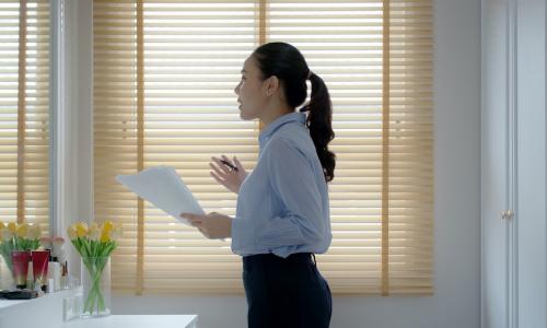 young Asian businesswoman practices presentation in front of bathroom mirror 