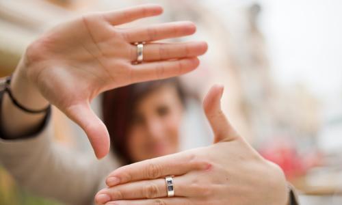 businesswoman out of focus in background holds out hands to form a square window in sharp focus in foreground