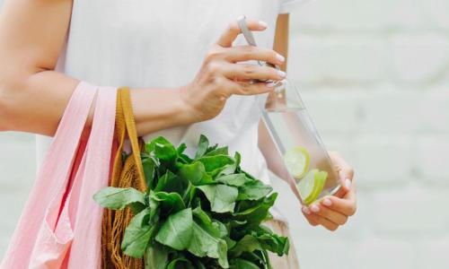 woman with greens in shopping bag and a water bottle