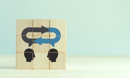 wooden blocks with silhouettes of faces communicating feedback to each other 