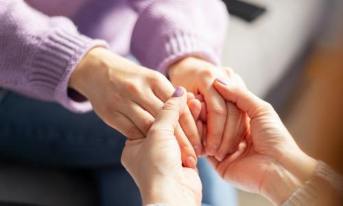 female colleague holding the hands of another employee to show care and support