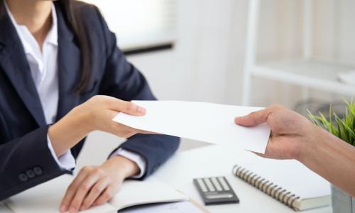 HR manager hands employee bonus check in envelope