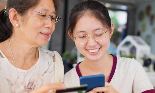 Asian woman and girl use credit card and smartphone