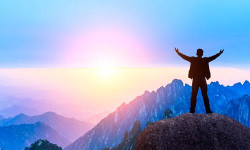 man with outstretched arms atop mountain