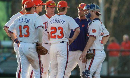 Baseball team infielders meet with coach on the pitcher’s mound