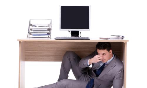 stressed tired business manager hiding under office desk