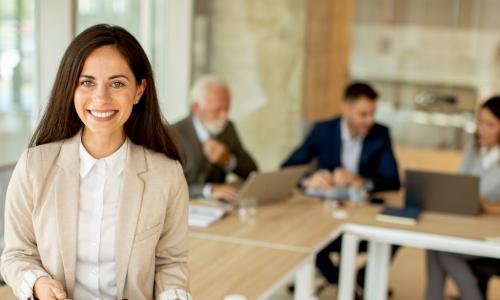 CEO sitting on table with tablet and team behind her