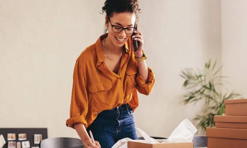 smiling business owner talks on phone in home office