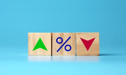 wooden blocks with a green up arrow a percent sign and a red down arrow representing interest rates