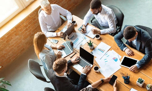 overhead view of diverse group of business colleagues working together at meeting table