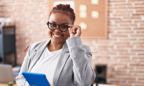 smiling African American woman puts on glasses